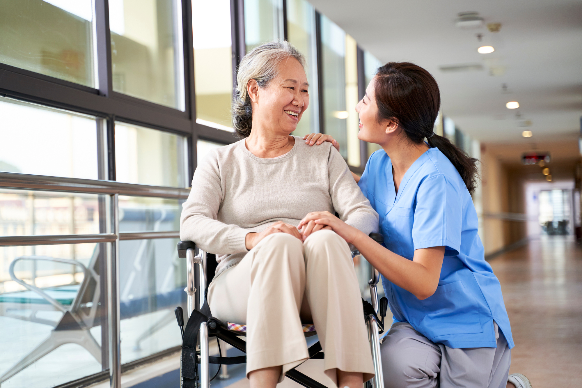 A nurse assists an elderly woman in a wheelchair